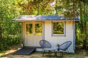 a tiny house with two chairs and a table at A Tiny House Near The Beach in Pērkone +14 photos