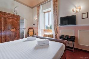 a bedroom with a large bed and a tv on the wall at Villa Ape Rosa Relais in Florence