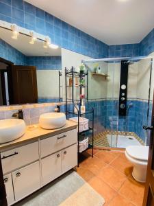 uma casa de banho em azulejos azuis com 2 lavatórios e um chuveiro em Apartamento Rural La Bandolera em El Bosque