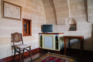 a room with a tv and a chair and a table at Gul Konakları - Sinasos - Special Category in Urgup