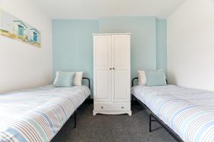 a bedroom with two beds and a white cabinet at Host & Stay - Blacksmith's Cottage in Amble