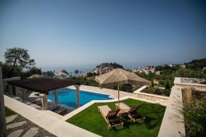a villa with a swimming pool and two patio chairs at Elysium Living Parga in Parga