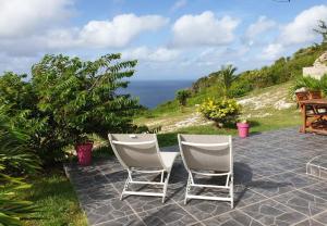 2 sedie sedute su un patio con vista sull'oceano di Habitation Noelesse a Beauregard