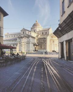 a large building with tables and chairs in front of it at The Galileo Apartment in Pisa