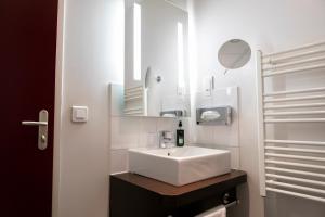 a white sink sitting under a mirror in a bathroom at The Originals Residence KOSY appart'hôtels - Les Cèdres in Grenoble