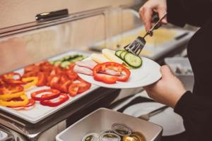 a person holding a plate with vegetables on it at Heritage Hotel Hallstatt in Hallstatt