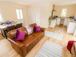 ein Wohnzimmer mit einem braunen Sofa und lila Kissen in der Unterkunft Caldey Lodge Bier Wood Lodges in Tenby