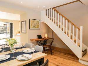 a dining room with a table and a staircase at Hugill Cottage in Kendal