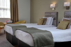 a hotel room with two beds and a desk at Hellaby Hall Hotel, BW Signature Collection in Hellaby