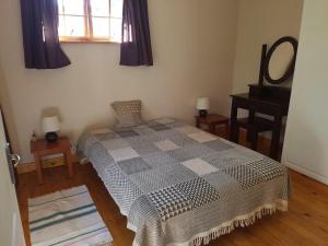 1 dormitorio con cama, espejo y piano en Natures Cabin, en Hibberdene