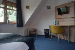 a bedroom with a bed and a desk with a television at HOTEL BIKE & HIKE in Obersuhl