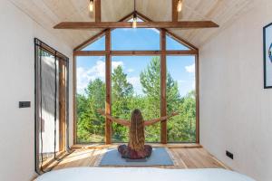 une femme assise dans une pièce donnant par une fenêtre dans l'établissement Üügumetsa treehouse, à Kallaste