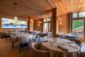 un comedor con mesas, sillas y ventanas en Le Chalet Blanc Hôtel & Spa en Montgenèvre