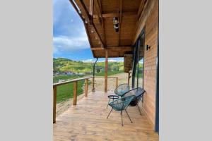 un portico con due sedie sul lato di un edificio di Valley House Cabana cu priveliste de vis a Sita Buzăului