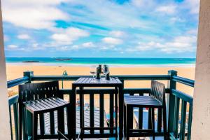 a table and two chairs on a balcony overlooking the beach at Les Charmettes in Saint Malo