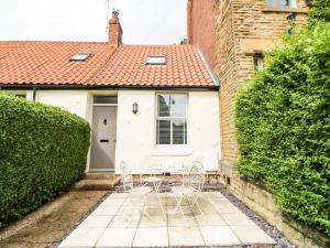 un par de sillas frente a una casa blanca en 22A Taylors Cottage en Whitley Bay