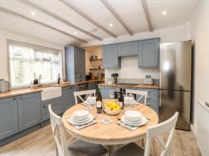 eine Küche mit blauen Schränken sowie einem Holztisch und Stühlen in der Unterkunft 22A Taylors Cottage in Whitley Bay