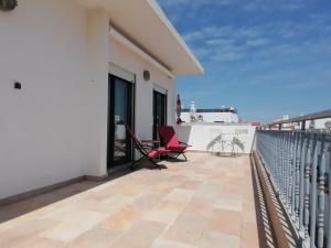 un balcone con sedie rosse su un edificio bianco di Cabanas Riverside a Cabanas de Tavira