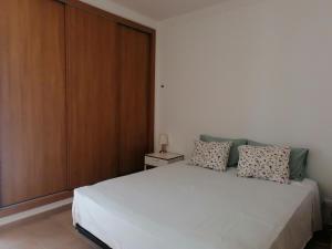 una camera da letto con un letto bianco e un armadio in legno di Cabanas Riverside a Cabanas de Tavira