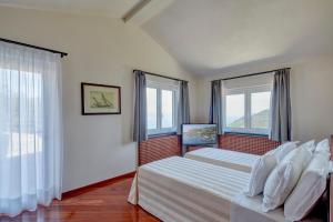 a bedroom with two beds and two windows at Il Leccio - Luxury Resort Portofino Monte in Santa Margherita Ligure