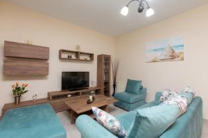 a living room with two blue chairs and a television at Afroditi´s House in Ipsos