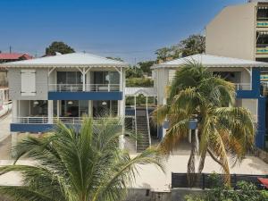 une maison avec des palmiers devant dans l'établissement Villa Lili, à Les Trois-Îlets