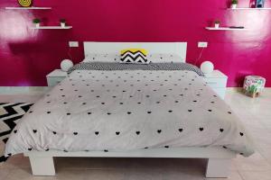 um quarto com uma cama branca e uma parede rosa em L'attico delle Meraviglie - SUITE BellaVista em Santa Maria degli Angeli