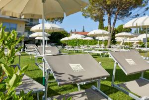 uma fila de mesas e cadeiras com guarda-sóis em Park Hotel Casimiro em San Felice del Benaco