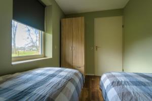 Schlafzimmer mit einem Bett und einem Fenster in der Unterkunft Waddenresidentie Ameland in Buren