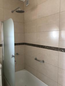 a bathroom with a shower with a white tub at Edificio Soles in Puerto Madryn +23 photos
