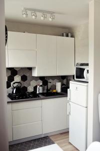 a kitchen with white cabinets and a white refrigerator at Na chmury i góry - apartament in Kłodzko