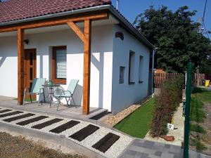 a small white house with a table and chairs at Kaland apartman 1 in Sátoraljaújhely