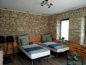 a bedroom with two beds and a stone wall at Kaland apartman 1 in Sátoraljaújhely
