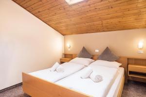two beds in a room with wooden ceilings at Apt Hofer Heidi in Villabassa