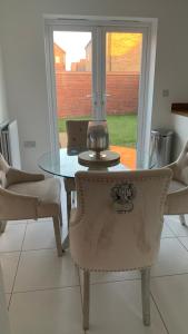 a glass table and chairs in a room with a window at Stanton Cross 5 persons 3 Bed Home in Wellingborough