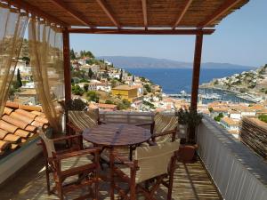 una mesa y sillas en un balcón con vistas al océano en Hydra's View House, en Hydra