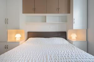 a bedroom with a white bed with two lamps at Teranino Apartment in Dubrovnik