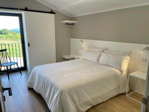 1 dormitorio con cama blanca y balcón en Casa Galego en Fonfría