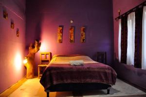 um quarto com uma cama num quarto roxo em Giramundo Hostel Purmamarca em Purmamarca