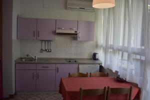 a kitchen with purple cabinets and a table with chairs at Podgora Apartmani Sonja in Podgora