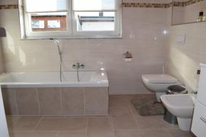 ein Badezimmer mit Badewanne, Toilette und Waschbecken in der Unterkunft Ferienhaus 1 - 55483 Unzenberg in Göbenhausen + 8 Fotos