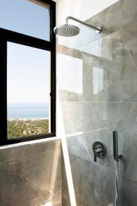 a bathroom with a shower with a large window at Wait 'n Sea in Himare