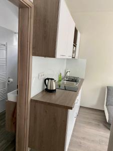 małą kuchnię z białymi szafkami i zlewem w obiekcie Tempó Apartman Siófok w Siófoku