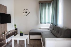 salon z kanapą i zegarem na ścianie w obiekcie Tempó Apartman Siófok w Siófoku