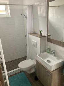 a white bathroom with a toilet and a sink at Tempó Apartman Siófok in Siófok