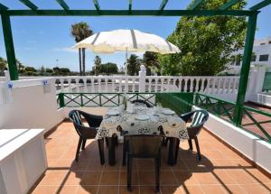 stół z krzesłami i parasol na patio w obiekcie Nicole Playa Park w Puerto del Carmen