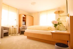 1 dormitorio con 1 cama con un jarrón de flores sobre una mesa en Hotel Morgensonne en Badenweiler