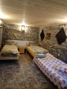 two beds in a room with a stone wall at Ковачевата къща село Миндя in Mindya