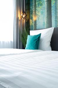 1 cama con sábanas blancas y almohada azul en Gästehaus&Pension Pinske en Saalburg