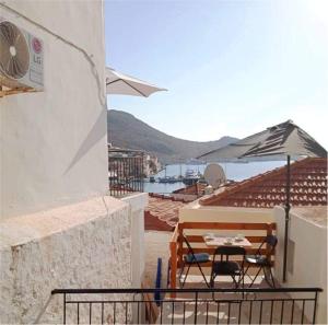 a table and chairs under an umbrella on a balcony at Occasus Room Comfort in Halki